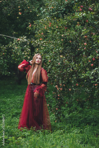 A beautiful young woman in a bard dress is gazing on in the field and the garden.