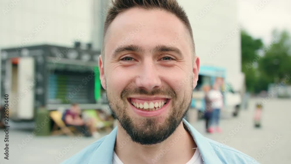 A man with a beard smiling in the city street full of people. Close-up shot. Soft focus A man with a beard smiling in the city street full of people. Close-up shot. Soft focus