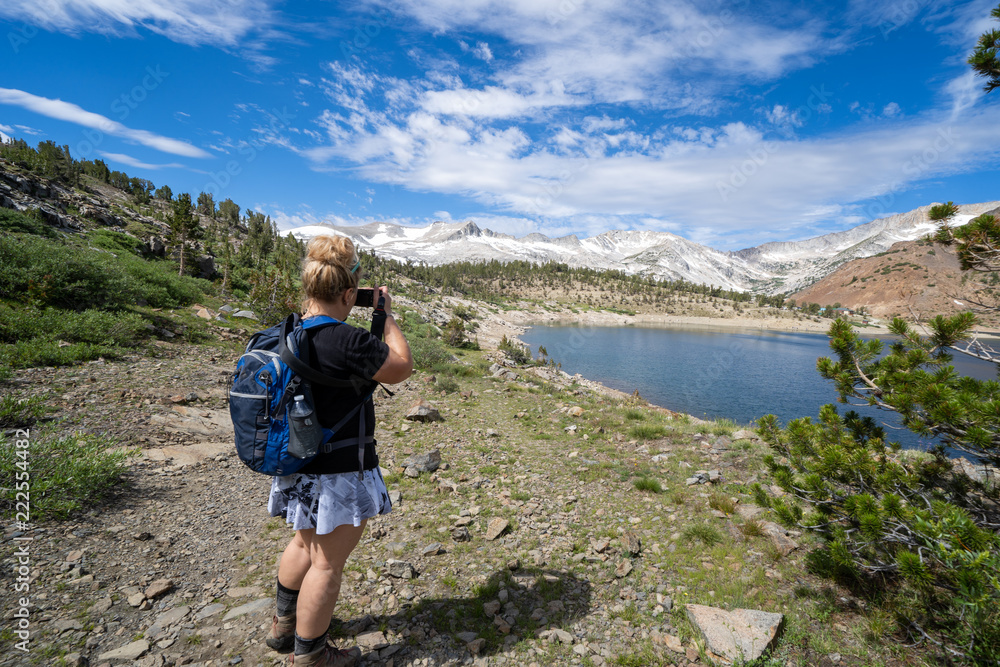 Female backpacker takes photos of Saddlebag Lake in the Eastern Sierra mountains of California