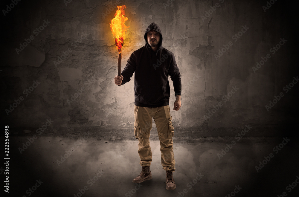 Ugly wayfarer with burning torch in his hand in front of a crumbly wall concept
Ugly wayfarer with burning torch in his hand in front of a crumbly wall concept