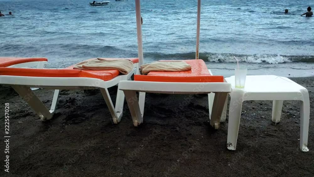 4k video of empty sunbeds and people swimming in sea during rain 4k video of empty sunbeds and people swimming in sea during rain