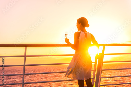 Luxury cruise ship travel elegant woman drinking glass of champagne enjoying watching sunset from boat deck over ocean in Europe destination vacation. Cruising sailing away on holiday.