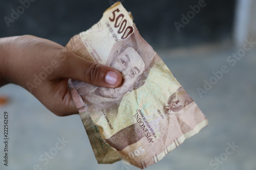 Holds Indonesian money worth 5,000 rupiah