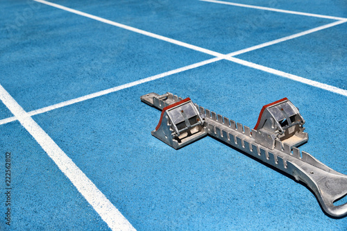 Starting blocks on blue running tracks lanes at track and field stadium. Sport accessory. photo