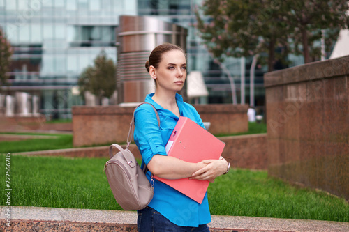 Young attractive girl is holding a folder for documents. Manager pensively looked into the distance.