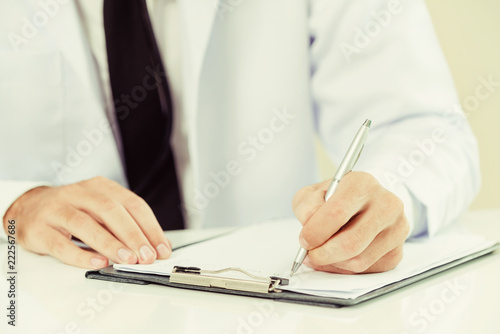 Doctor in hospital writing on a paper document. photo