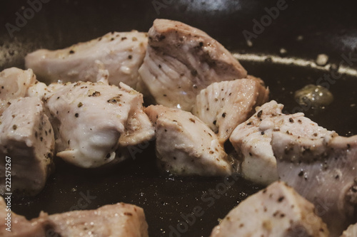 Close up view of seasoned grilling chicken within a skillet