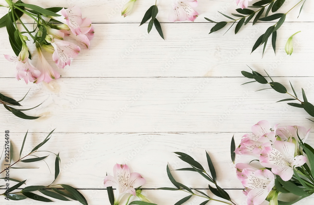 Flowers background. Frame from beautiful pink flowers and eucalyptus branches on white wooden background.Top view.Copy space Flowers background. Frame from beautiful pink flowers and eucalyptus branches on white wooden background.Top view.Copy space
