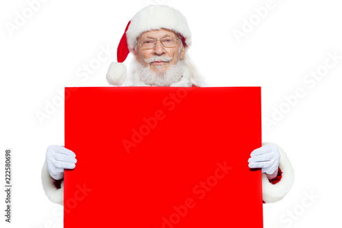 Christmas. The kind Santa Claus in white gloves holds an empty cardboard of red color. Place for advertising, for text, empty space. Copy-paste. Isolated on white background. © satyrenko