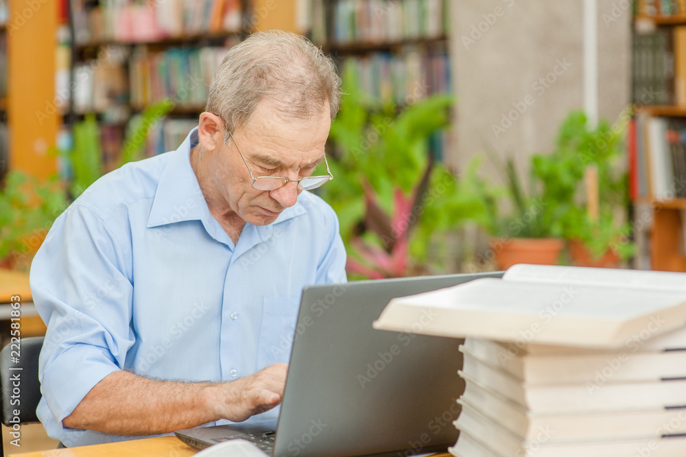Senior man using laptop in library Senior man using laptop in library