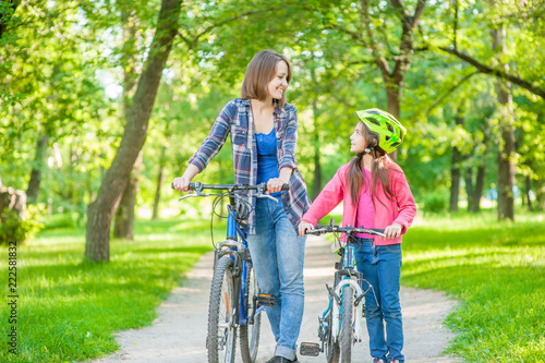 Mom and daughter are cycling in the park together. Space for text