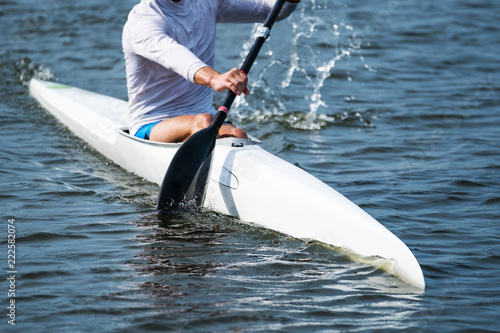 Photo of a part of a kayak with a paddle and a rower.