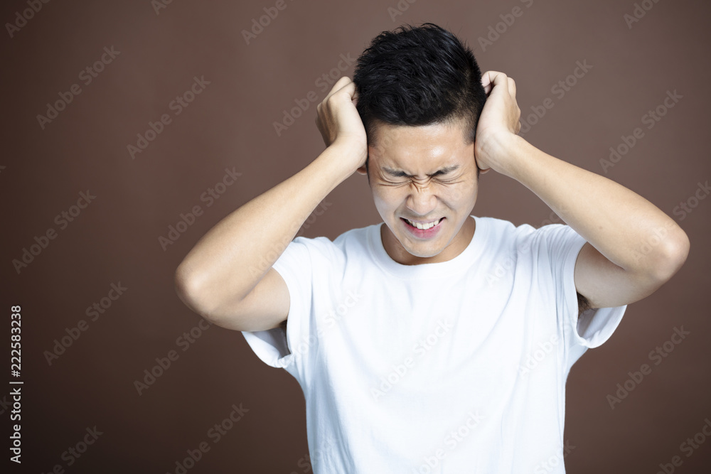 stressed young man holding on to head stressed young man holding on to head