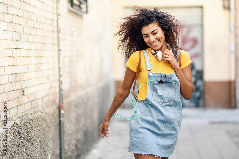 Young African woman with headphones walking outdoors Young African woman with headphones walking outdoors