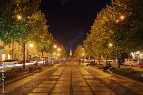 Nocny pejzaż Częstochowy, Polska, główna Aleja Najświętszej Panny Maryi, piękne drzewa po obu stronach, na horyzoncie wieża katedry na Jasnej Górze, długie naświetlanie