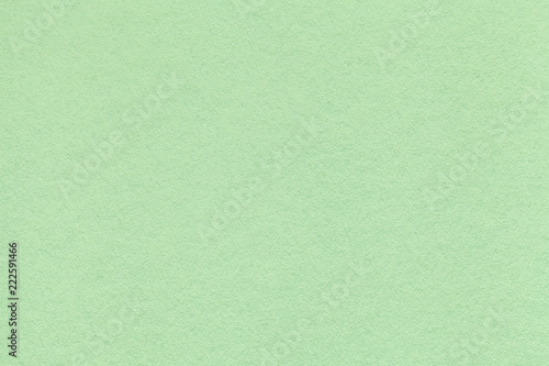 Texture of old light green paper closeup. Structure of a dense cardboard. The mint background.