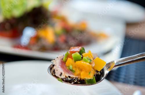 Grilled tuna steak slices with mango salsa and vetgetable salad on spoon photo