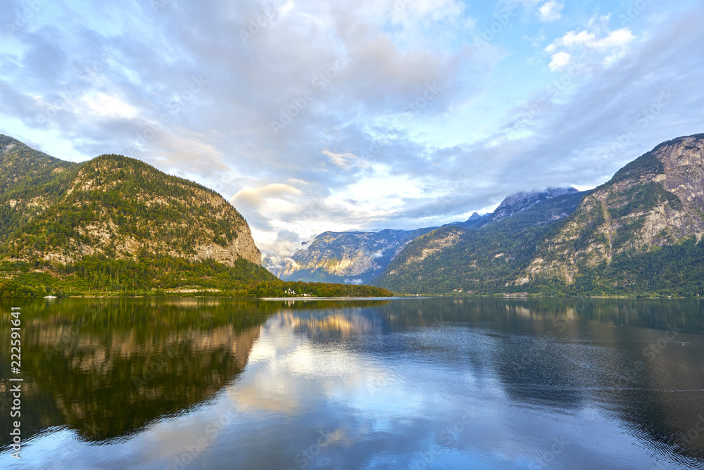 Fototapeta premium Scenic view of Hallstatter lake with a rainbow in Austrian Alps. Autumn sunset on Hallstatt lake with beautiful clouds and reflections of the sky in the water