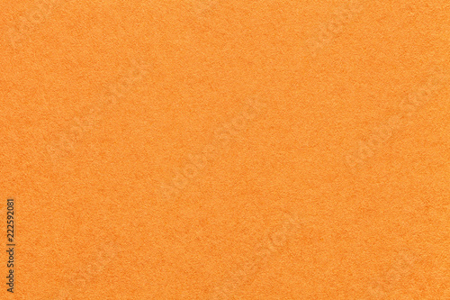 Texture of old bright orange paper background, closeup. Structure of dense carrot cardboard