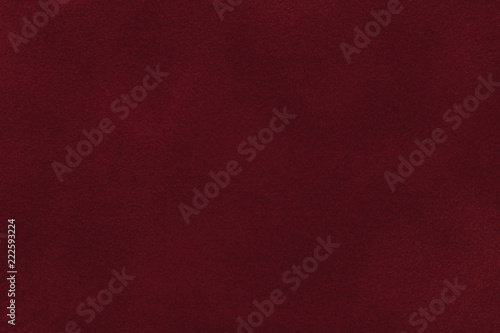 Background of dark red suede fabric closeup. Velvet matt texture of wine nubuck textile