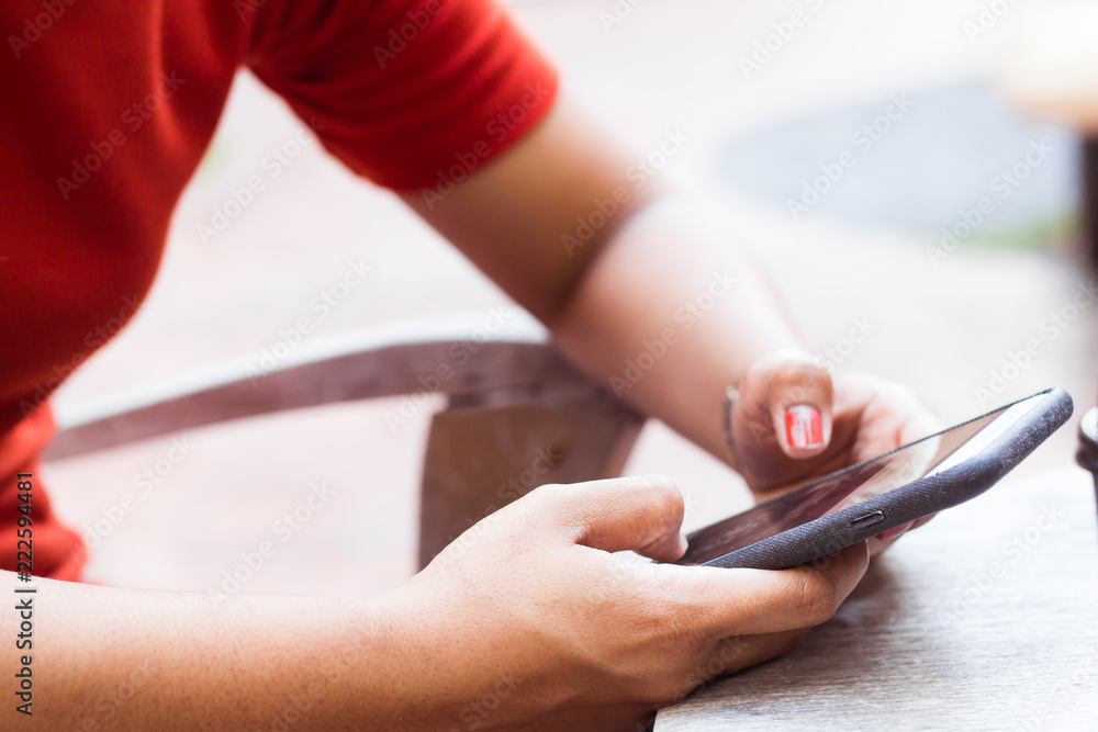 Young girl are playing Internet on mobile phones on a wood table.