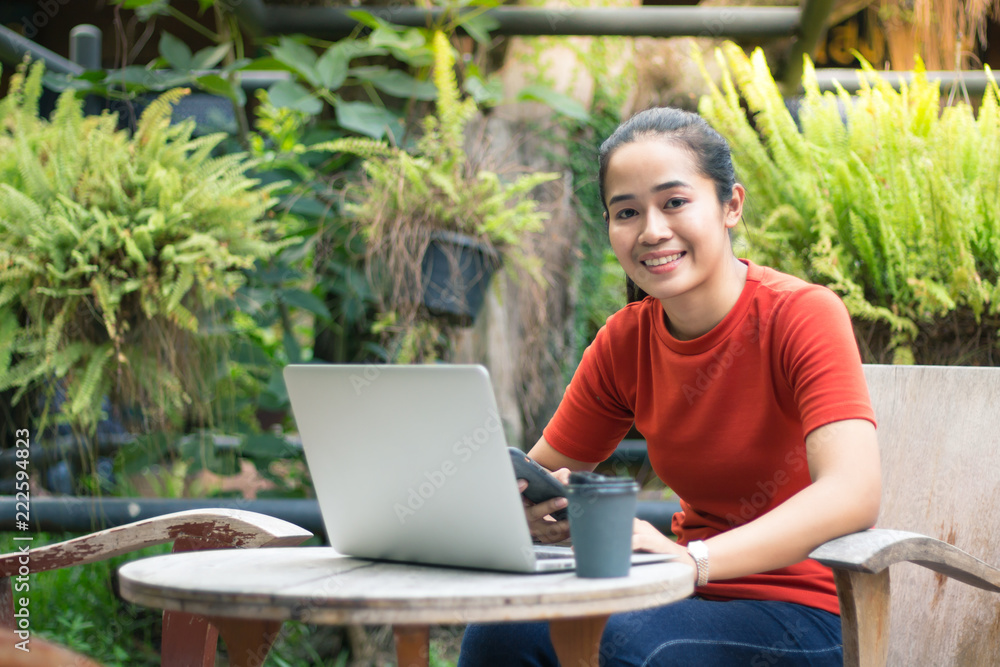 Women are smile and playing internet on mobile phones and have computer notebook and coffee cup on a wood table. Women are smile and playing internet on mobile phones and have computer notebook and coffee cup on a wood table.