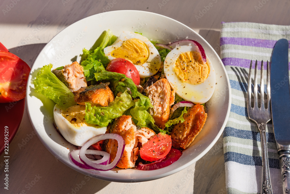 Healthy diet salad with salmon, tomatoes, eggs, onion and lettuce, top view. Dietary lunch