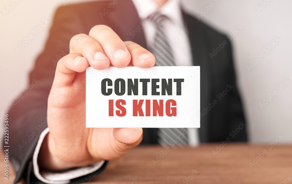 Businessman holding a card with text Content is King Businessman holding a card with text Content is King