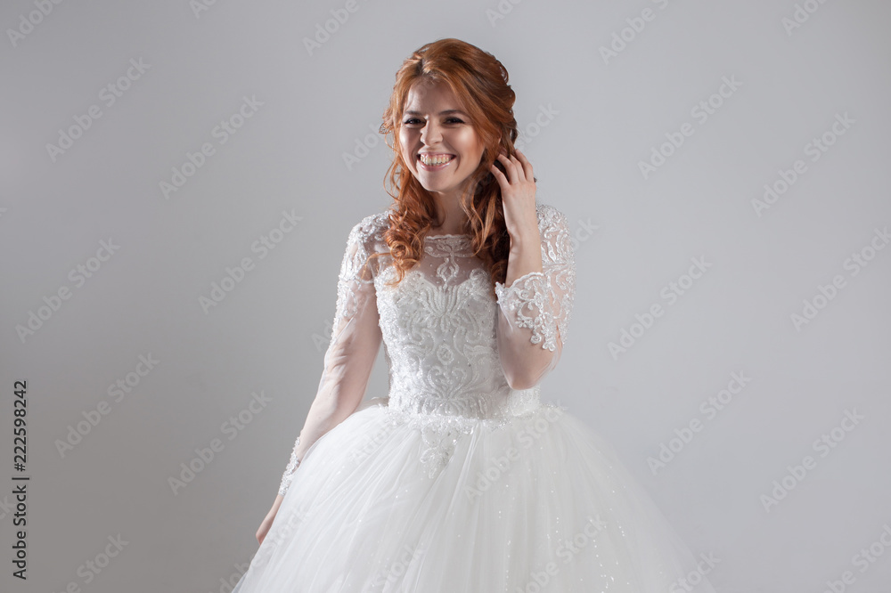 Happy laughing young woman in wedding dress. Charming bride on Light background.