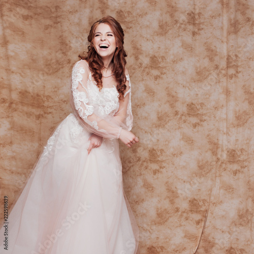 Obraz na plátně Happy laughing young woman in wedding dress with long sleeves