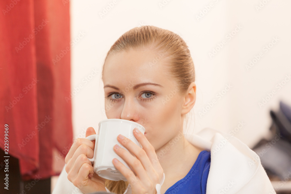 Woman lying on sofa under blanket drinking tea Woman lying on sofa under blanket drinking tea