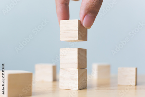 Hand arranging wood block stacking on top with wooden table. Business concept for growth success process