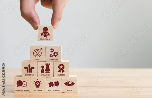 Hand arranging wood block stacking with icon leader business. Key success factors for leadership elements concept photo