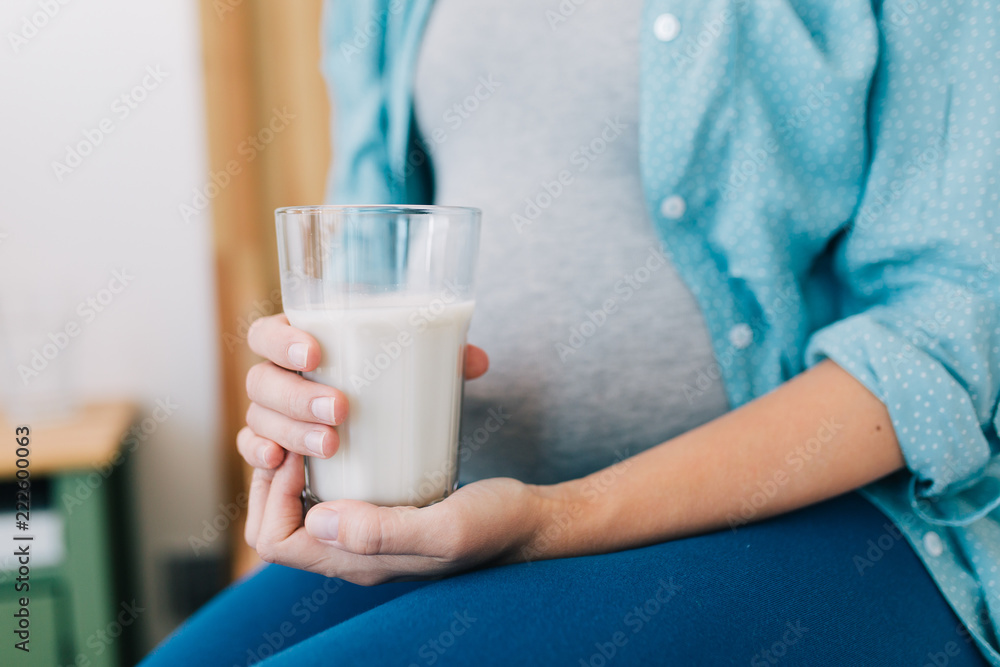 Beautiful young pregnant woman with glass of milk at home . Beautiful young pregnant woman with glass of milk at home .