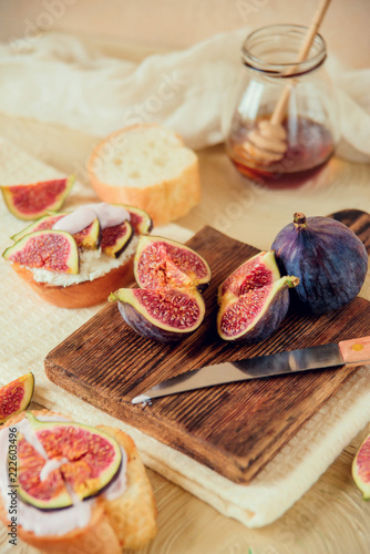 Autumn dessert: bruschetta with ripe figs, soft cheese and honey on a light background.