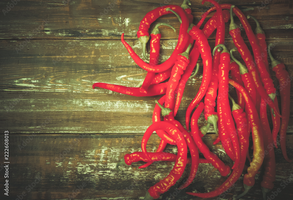Naklejka premium The composition of chili red hot peppers on wooden table