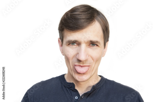 A man on a white background smiles and shows humorously the tongue. Isolated