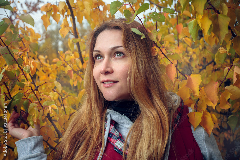 Portrait of a young blonde girl with green eyes and long hair in yellow autumn leaves. Close-up, flash light Portrait of a young blonde girl with green eyes and long hair in yellow autumn leaves. Close-up, flash light