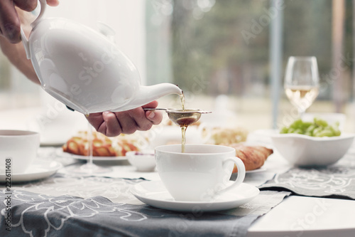 Tableau sur toile Close-up shot of man’s hands preparing tea-set with beautiful luxury elegant porcelain dishes