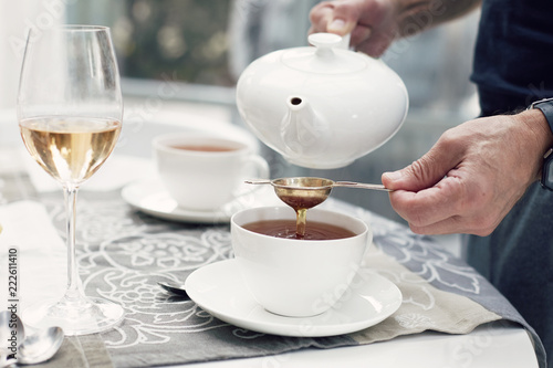 Close-up shot of man’s hands preparing tea-set with beautiful luxury elegant porcelain dishes. Traditional european breakfast preparation. Home and family concept.