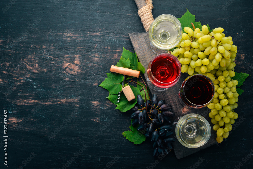 red and white wine in the glasses. Grape. On a black wooden background. Free space for text. Top view.