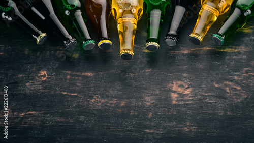 A large selection of beer bottles. On a black wooden table. Free space for text. Top view.