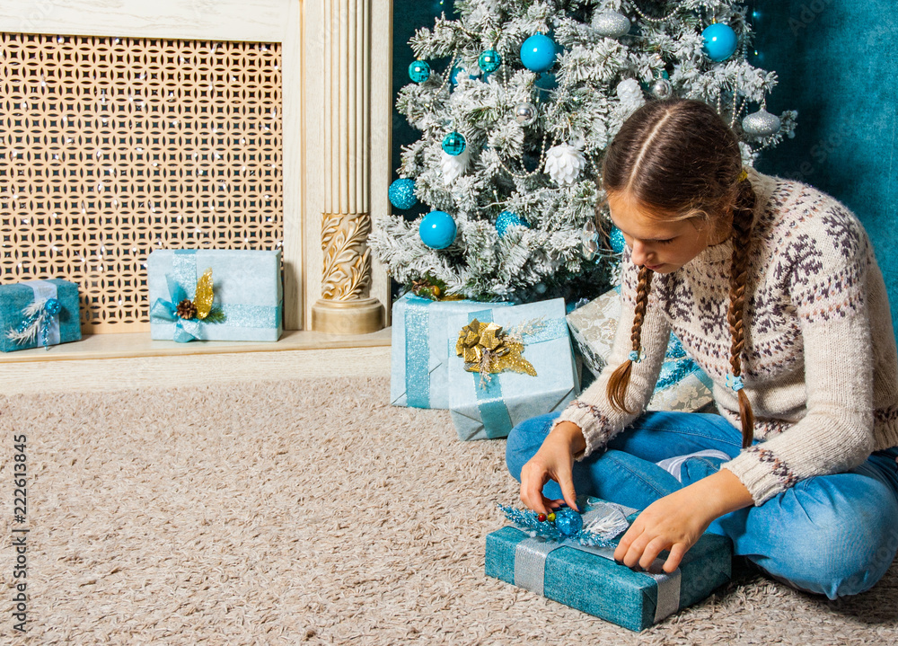 Naklejka premium teenager girl hold presents gift box on Christmas tree background