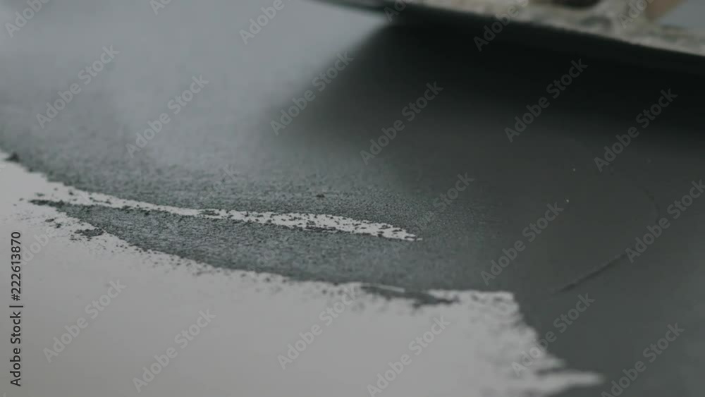 Slow motion closeup male worker applying micro concrete plaster coating on the floor with a trowel Slow motion closeup male worker applying micro concrete plaster coating on the floor with a trowel