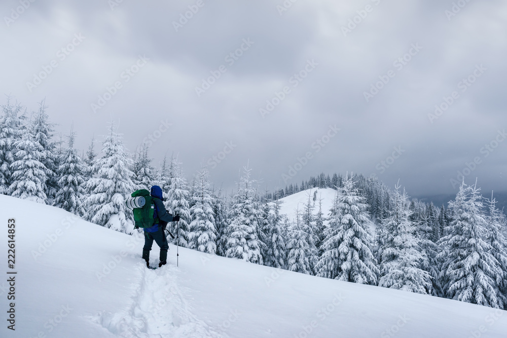 Alone tourist with a backpack in the high mountains in winter time. Travel concept