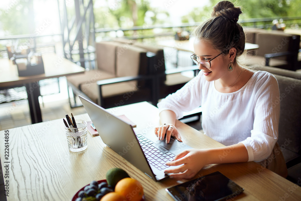 Young mixed race woman working with laptop in cafe at tropical location. Asian caucasian female studying using internet. Business woman doing social marketing work and shopping. Telecommuting concept. Young mixed race woman working with laptop in cafe at tropical location. Asian caucasian female studying using internet. Business woman doing social marketing work and shopping. Telecommuting concept.