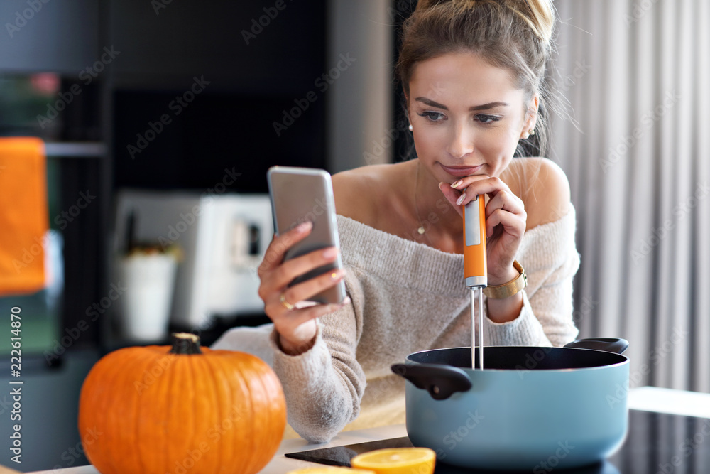 Adult woman in the kitchen preparing pumpkin dishes for Halloween Adult woman in the kitchen preparing pumpkin dishes for Halloween
