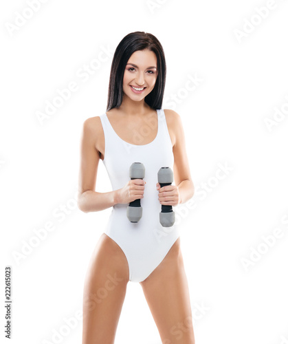 Young and fit girl pumping a dumbbells. Woman in sporty swimsuit. Sport, fitness and healthy lifestyle concept.