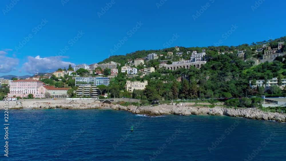 Mediterranean village near Nice in the green hills in sunshine light. rooftops and narrow streets below. mountains and sea in the distance. Summertime in France from aerial 4K drone view Mediterranean village near Nice in the green hills in sunshine light. rooftops and narrow streets below. mountains and sea in the distance. Summertime in France from aerial 4K drone view