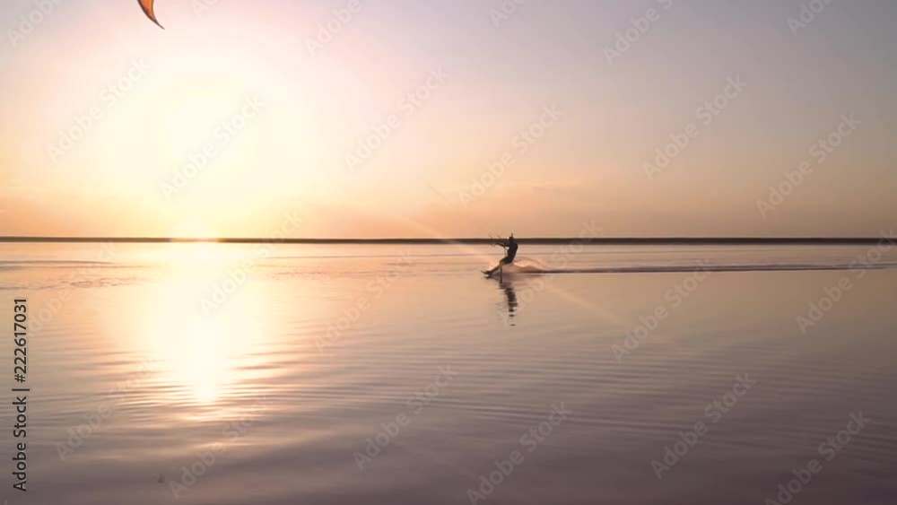 Dawn on the lake, a solitary kitesurfer in a helmet swims sideways Dawn on the lake, a solitary kitesurfer in a helmet swims sideways